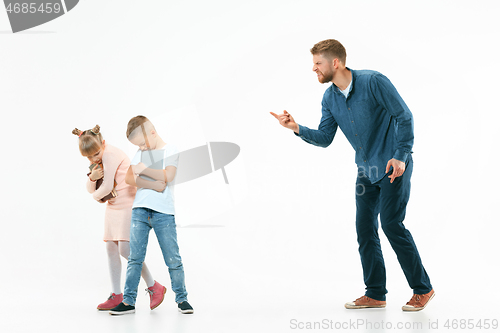 Image of Angry father scolding his son in living room at home