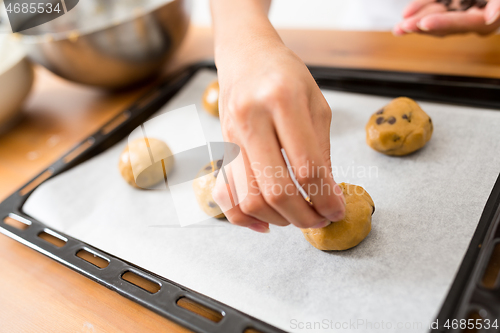 Image of Woman putting dough on metal tray