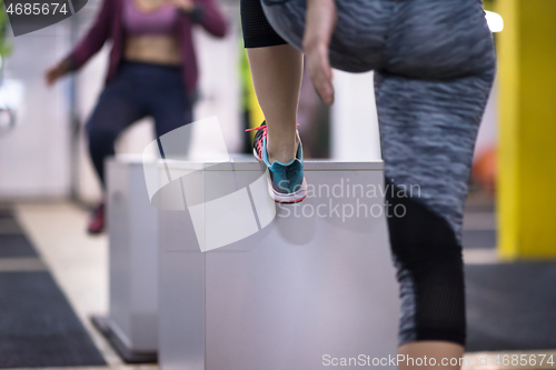 Image of athletes working out  jumping on fit box