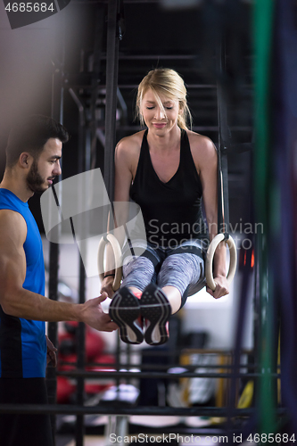 Image of woman working out with personal trainer on gymnastic rings