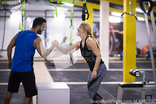 Image of woman working out with personal trainer jumping on fit box