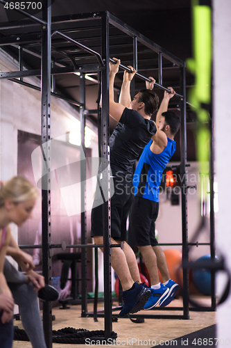 Image of young athletes doing pull ups on the horizontal bar