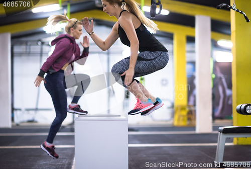 Image of athletes working out  jumping on fit box