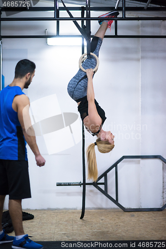 Image of woman working out with personal trainer on gymnastic rings