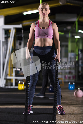 Image of athlete woman doing battle ropes cross fitness exercise