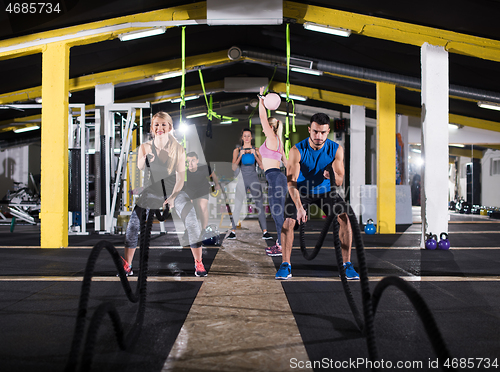 Image of sports couple doing battle ropes cross fitness exercise