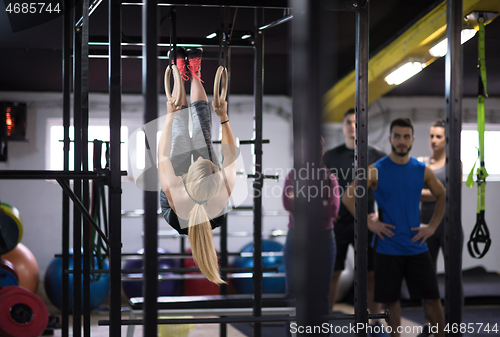 Image of woman working out with personal trainer on gymnastic rings