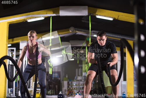 Image of sports couple doing battle ropes cross fitness exercise