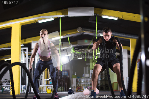 Image of sports couple doing battle ropes cross fitness exercise