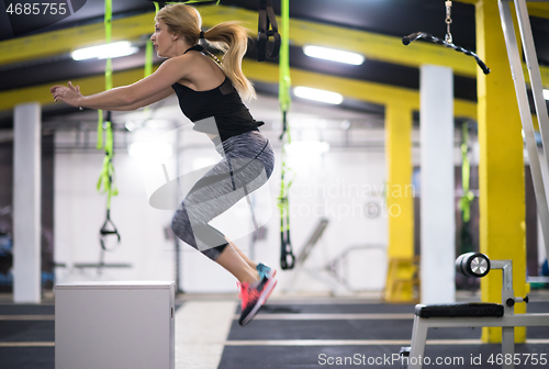 Image of woman working out  jumping on fit box