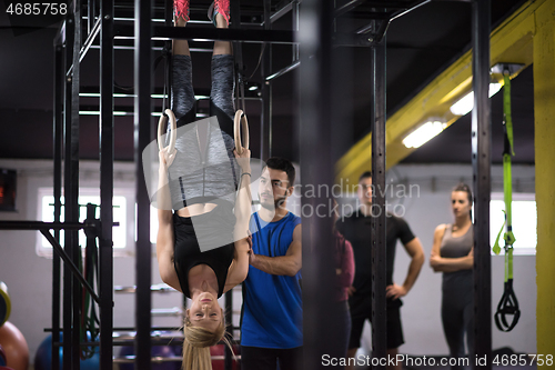 Image of woman working out with personal trainer on gymnastic rings