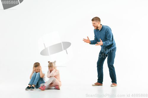 Image of Angry father scolding his son in living room at home