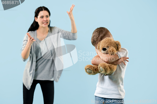 Image of Angry mother scolding her son in living room at home