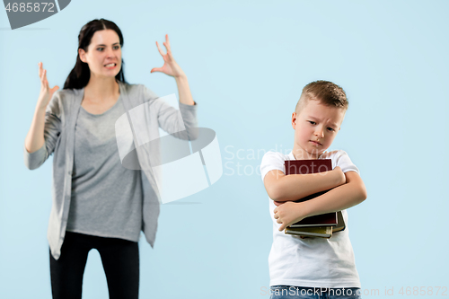 Image of Angry mother scolding her son in living room at home