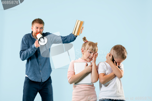 Image of Angry father scolding his son in living room at home