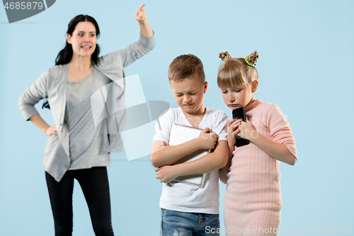 Image of Angry mother scolding her son in living room at home