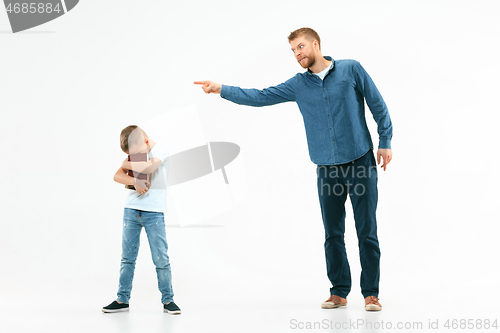 Image of Angry father scolding his son in living room at home