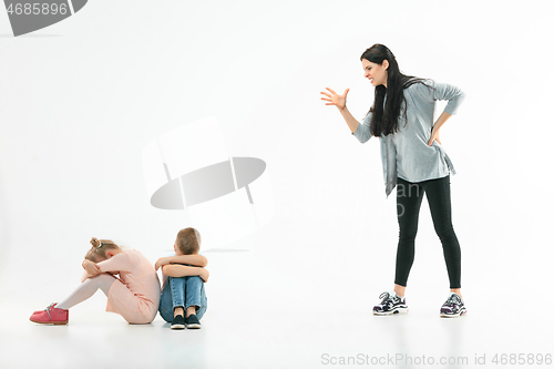 Image of Angry mother scolding her son in living room at home