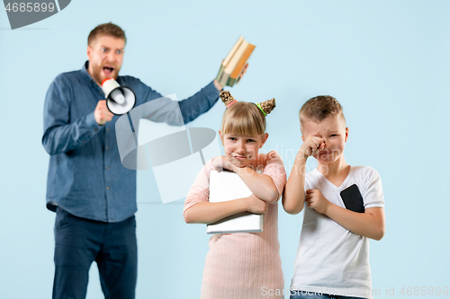 Image of Angry father scolding his son in living room at home