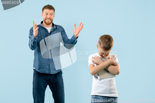 Image of Angry father scolding his son in living room at home