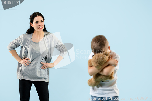 Image of Angry mother scolding her son in living room at home