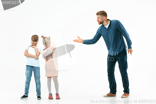 Image of Angry father scolding his son in living room at home