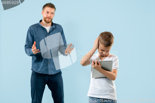 Image of Angry father scolding his son in living room at home