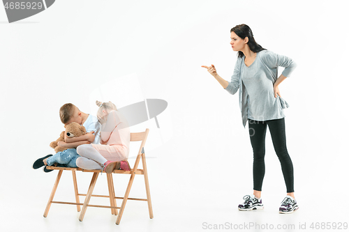 Image of Angry mother scolding her son in living room at home