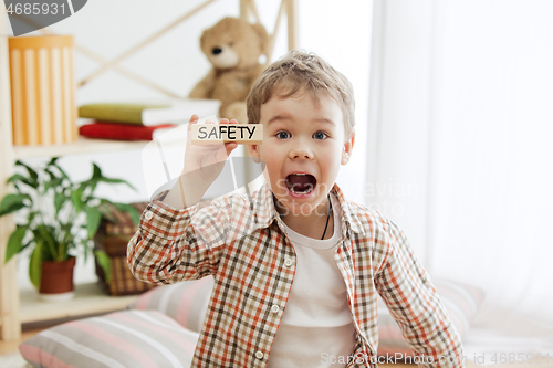 Image of Wooden cubes with word safety in hands of little boy