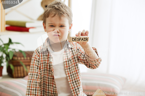 Image of Wooden cubes with word despair in hands of little boy