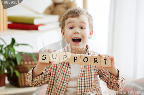 Image of Wooden cubes with word SUPPORT in hands of little boy