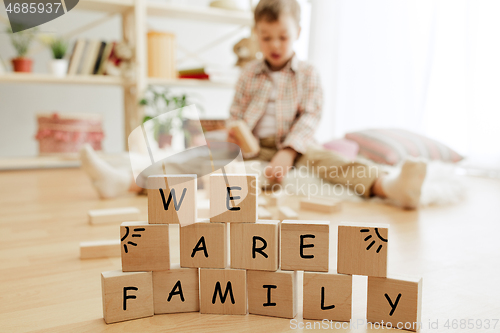 Image of Wooden cubes with words WE ARE FAMILY in hands of little boy