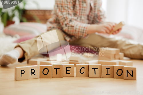 Image of Wooden cubes with word PROTECTION in hands of little boy