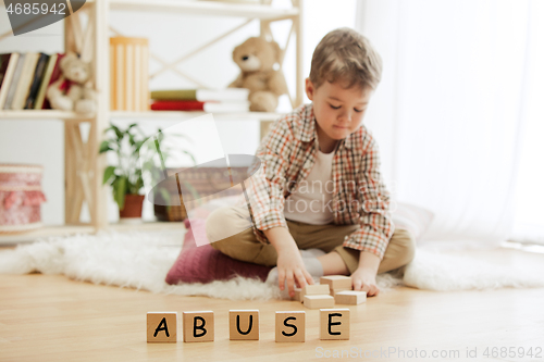 Image of Wooden cubes with word ABUSE in hands of little boy