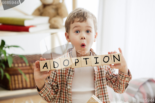 Image of Wooden cubes with word adobtion in hands of little boy