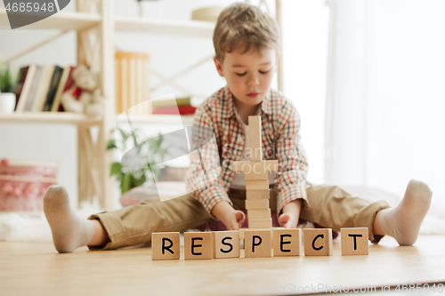 Image of Wooden cubes with word RESPECT in hands of little boy