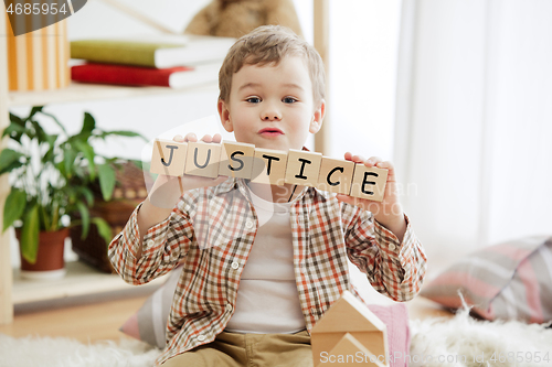 Image of Wooden cubes with word justice in hands of little boy