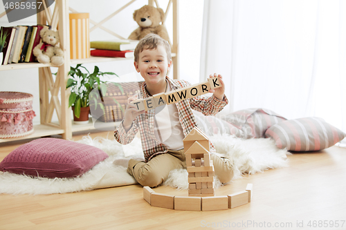 Image of Wooden cubes with word TEAMWORK in hands of little boy