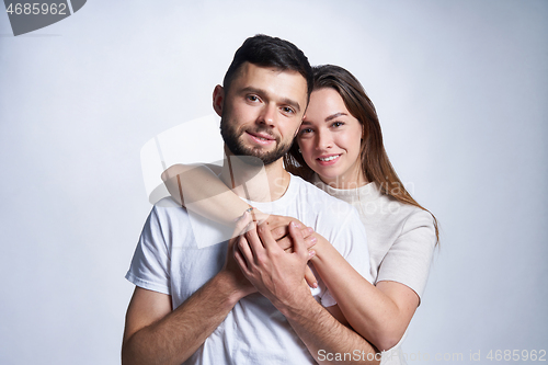 Image of Smiling young couple hugging, studio portrait over light background