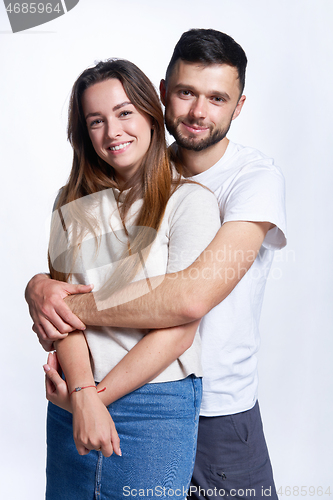 Image of Smiling young couple hugging, studio portrait over light background