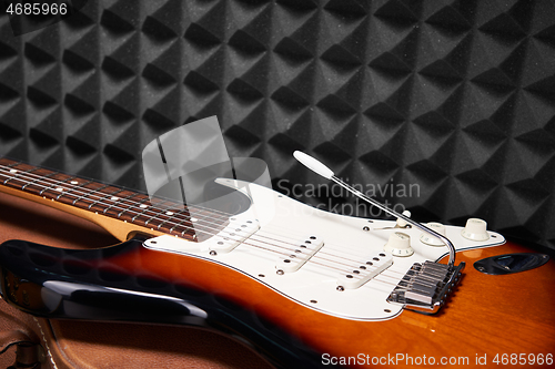 Image of Sunburst electric guitar lying on acoustic foam panel background