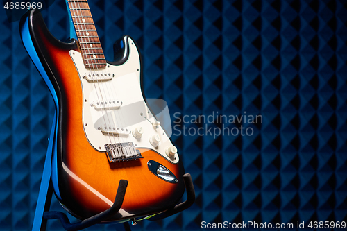 Image of Sunburst electric guitar standing over acoustic foam panel background