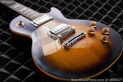 Image of Sunburst electric guitar lying on acoustic foam panel background