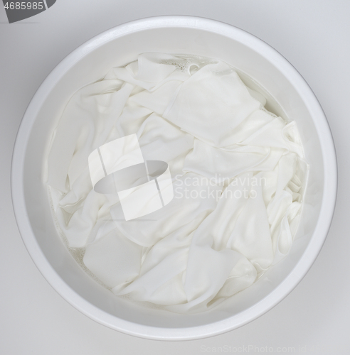 Image of washing white linen in a white plastic bowl 