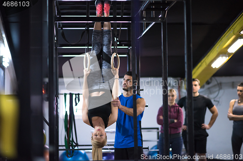 Image of woman working out with personal trainer on gymnastic rings