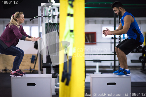 Image of athletes working out  jumping on fit box