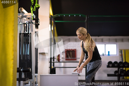 Image of woman working out  jumping on fit box