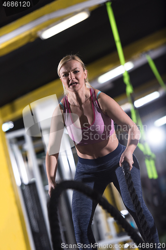 Image of athlete woman doing battle ropes cross fitness exercise