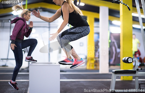 Image of athletes working out  jumping on fit box