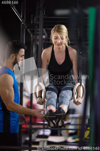 Image of woman working out with personal trainer on gymnastic rings